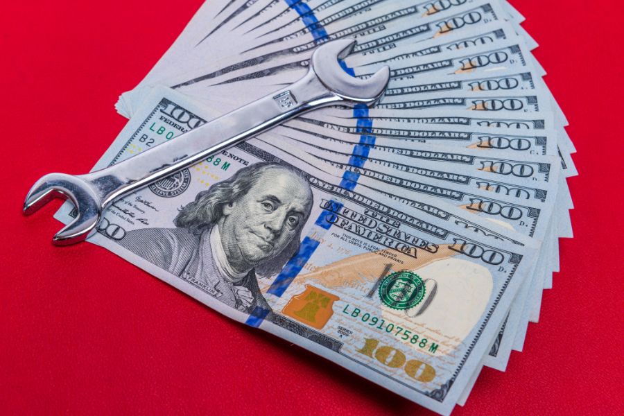 wrench and one hundred dollar bills on red background