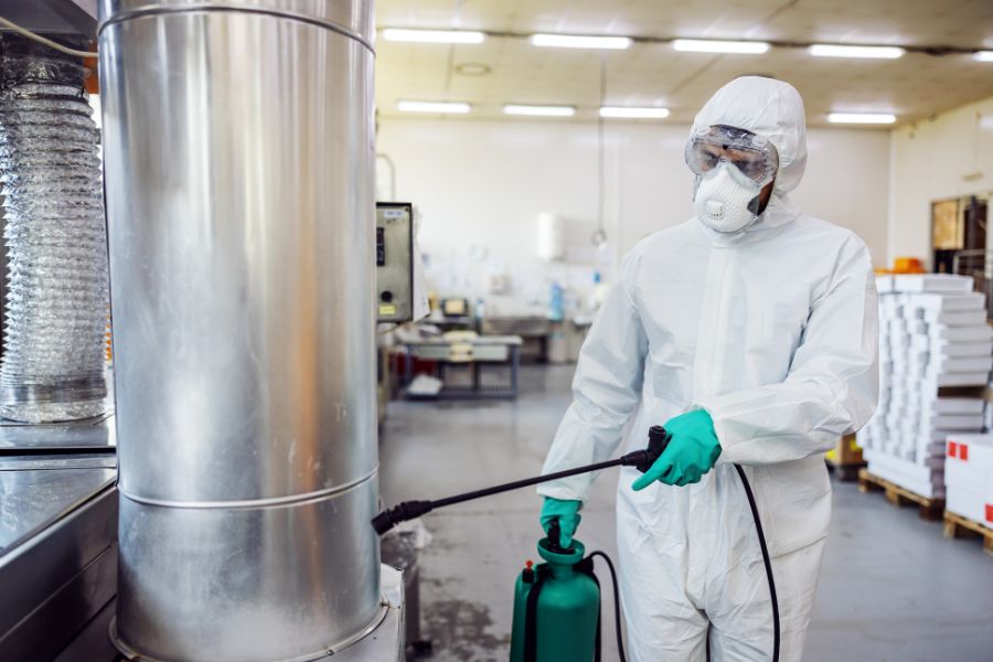 man in protective suit disinfecting food factory