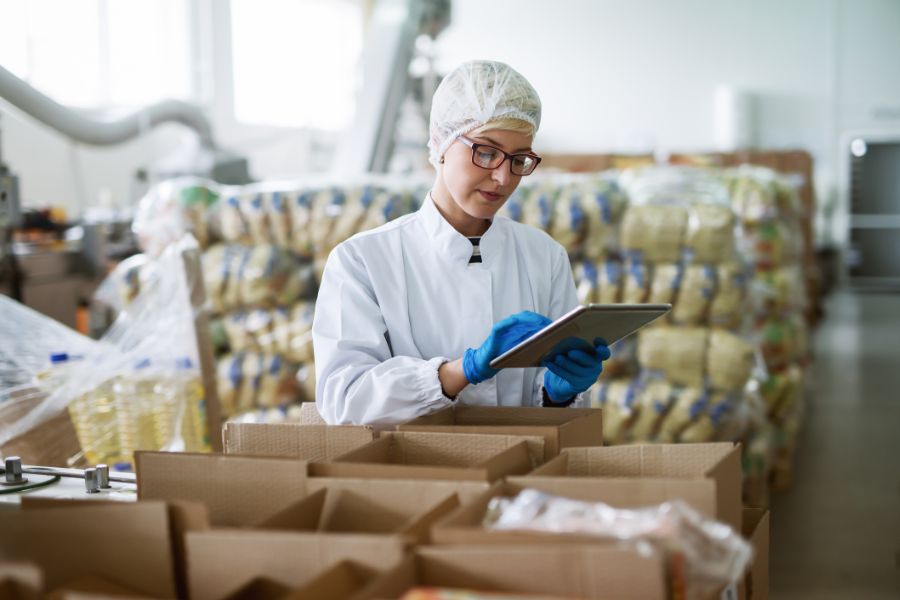 female worker using tablet for checking boxes in food factory