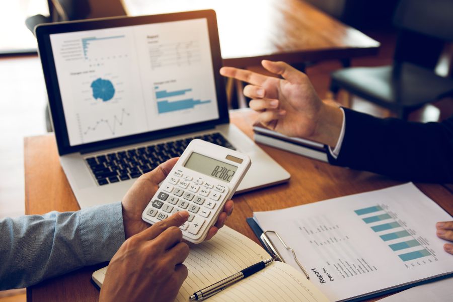 managers analyzing report using laptop and calculator