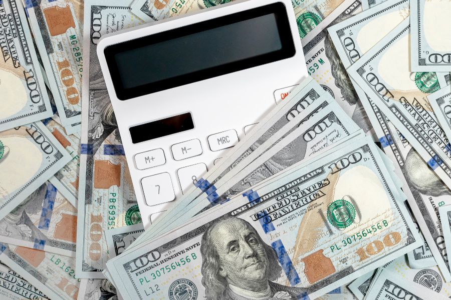 calculator and pile of dollar banknotes