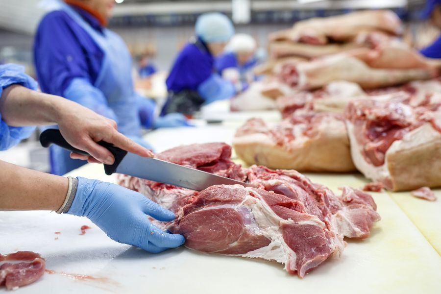 butcher cutting pork at meat manufacturing