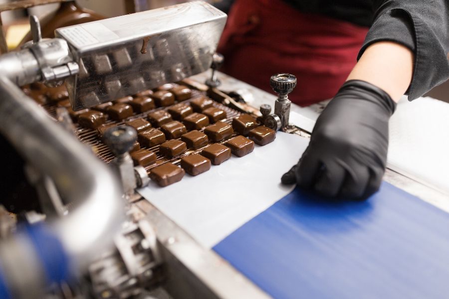 employee working in chocolate coating machine