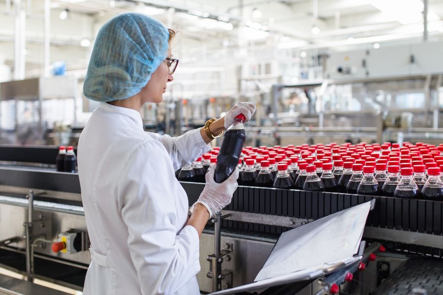 food factory worker inspecting bottled products