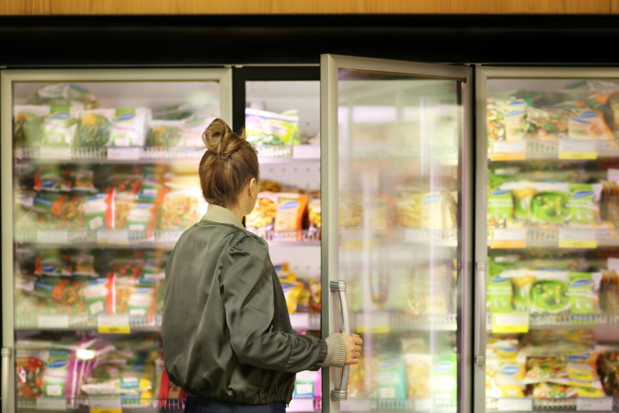 woman choosing frozen food from supermarket freezer