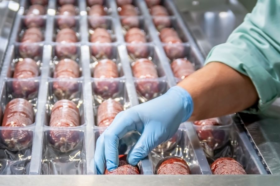 woman preparing sausages in production line
