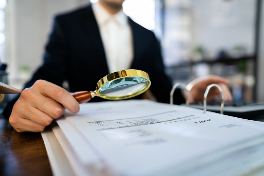 auditor using magnifying glass for reading documents